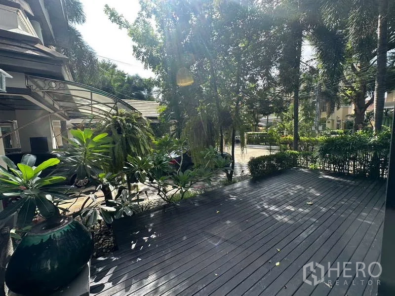 独立式住宅 出售在Suan Luang, Bangkok - 阳光露台，木地板与热带盆栽。