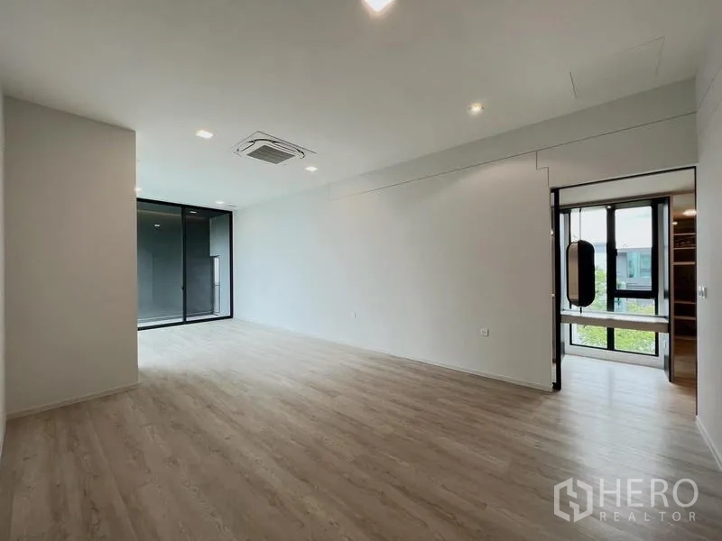 Detached House for rent or sale in Saphan Sung, Bangkok - Spacious bedroom with balcony access and doorway leading to a walk-in closet.