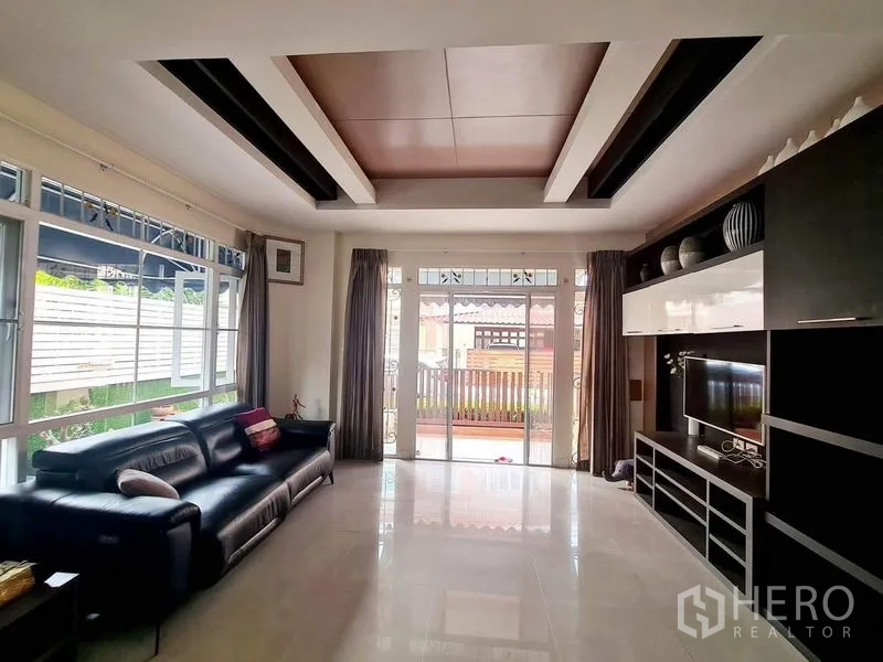Detached House for rent in Sai Mai, Bangkok - Bright living room with large windows, sectional sofa and sliding glass doors to the porch.