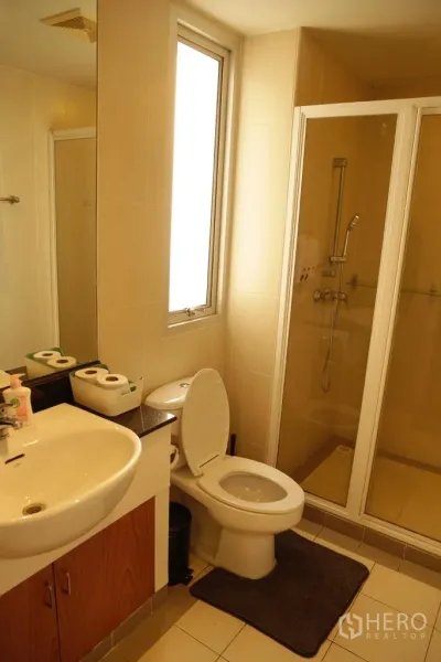 Condominium for rent or sale in Watthana, Bangkok - Bright bathroom with vanity, toilet and a glass-enclosed shower.