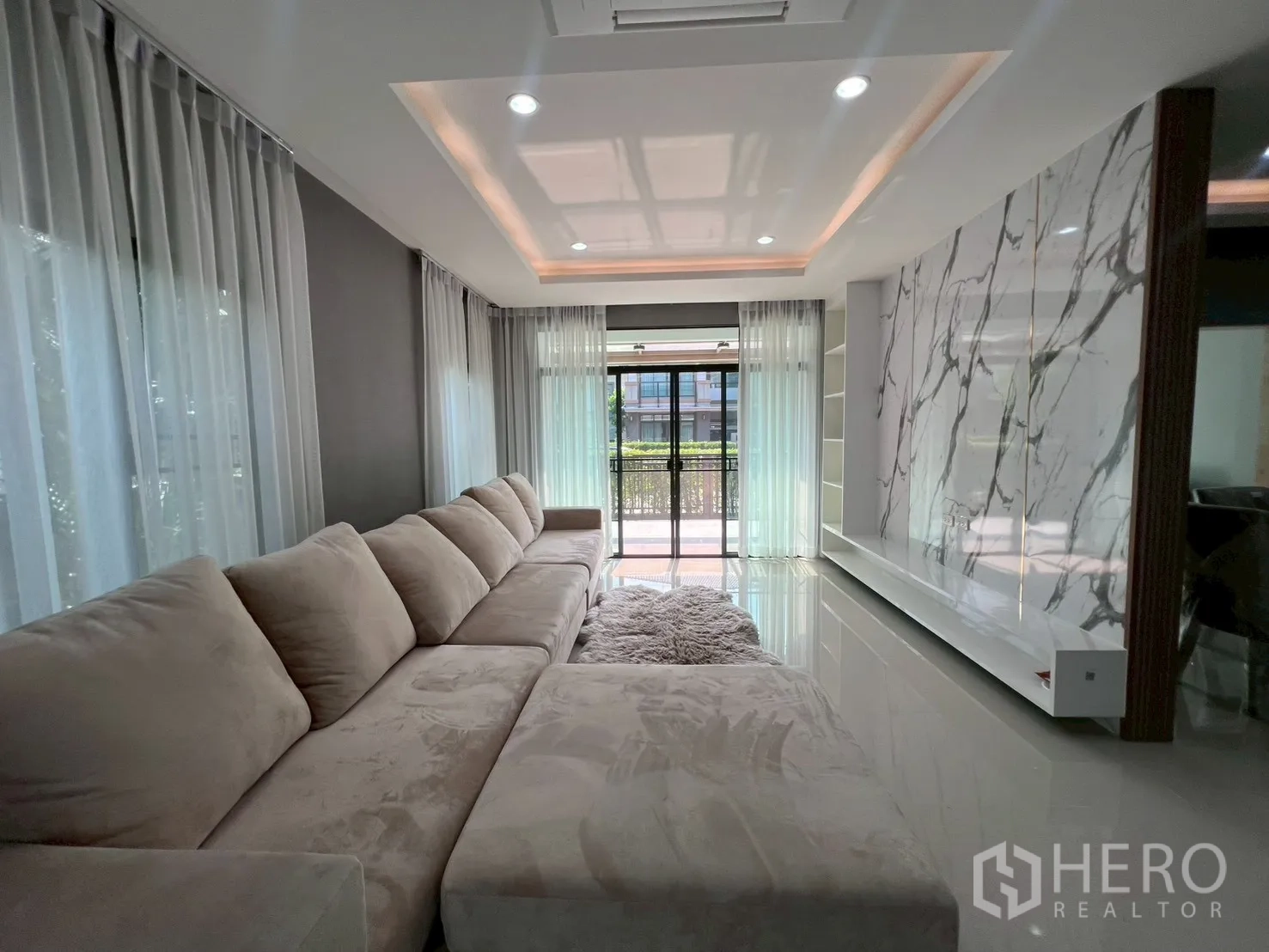 独立式住宅 出租或出售在Bang Phli, Samut Prakan - 狭长客厅，带大理石纹电视墙与通园景的滑门。