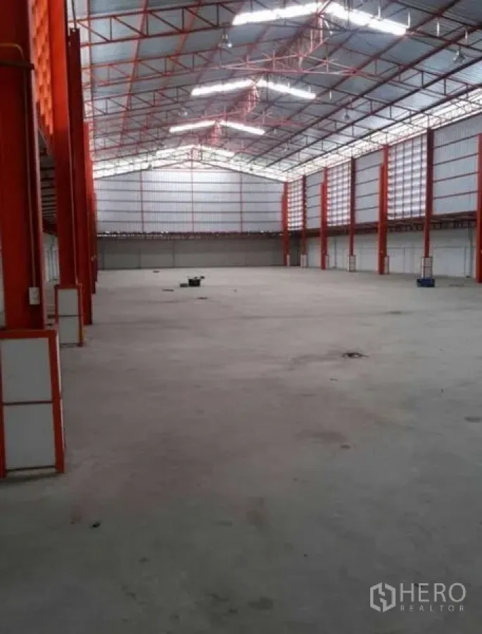 Warehouse for rent in Bang Phli, Samut Prakan - Long aisle perspective of warehouse with orange frames and translucent roof panels