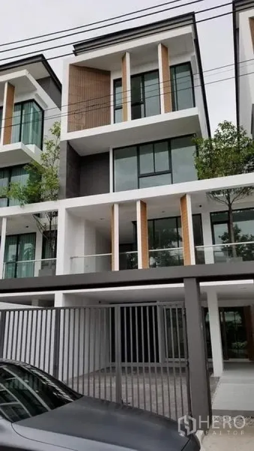联排别墅 出售在Lat Phrao, Bangkok - 现代多层联排别墅外立面，玻璃阳台、车棚与大门。