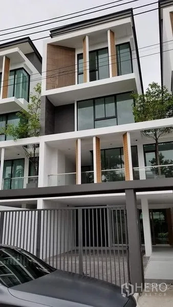 联排别墅 出售在Lat Phrao, Bangkok - 现代多层联排别墅外立面，玻璃阳台、车棚与大门。