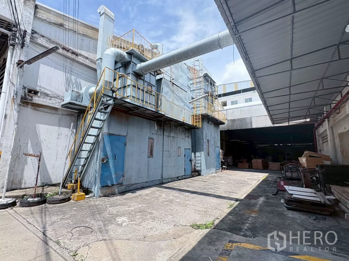 工厂 出租或出售在Bang Khun Thian, Bangkok - 建筑外侧的大型排风与管道系统，带金属楼梯和机房门。
