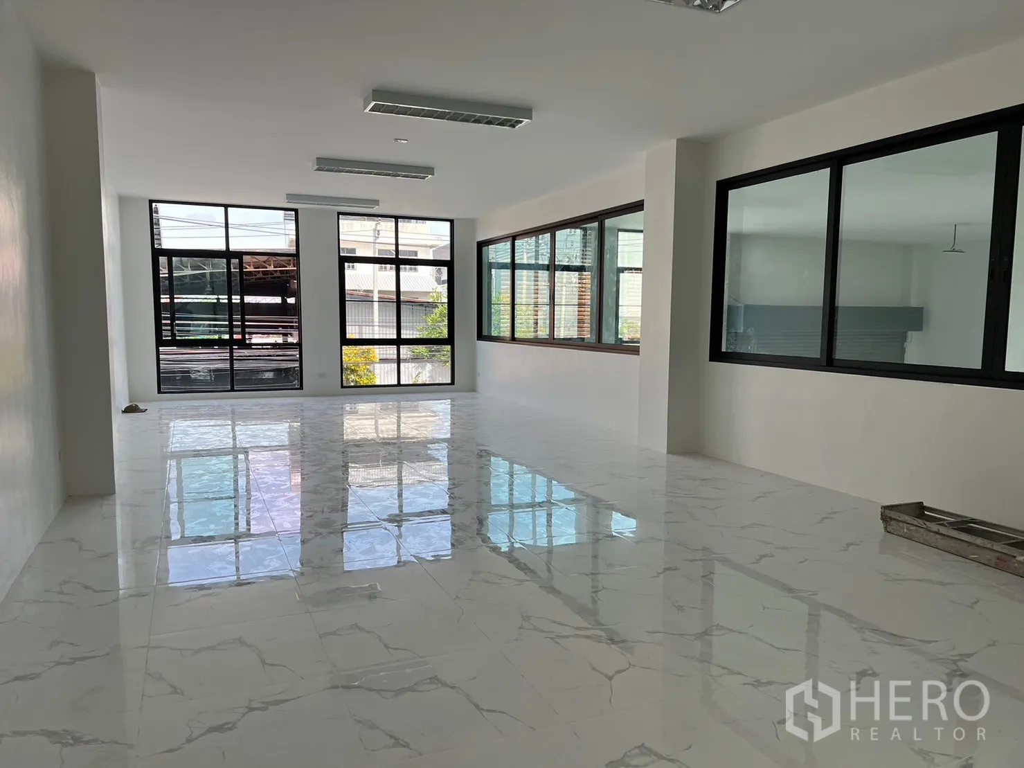 Warehouse for rent in Samut Prakan - Bright office floor with large windows and glossy marble-look tiles.