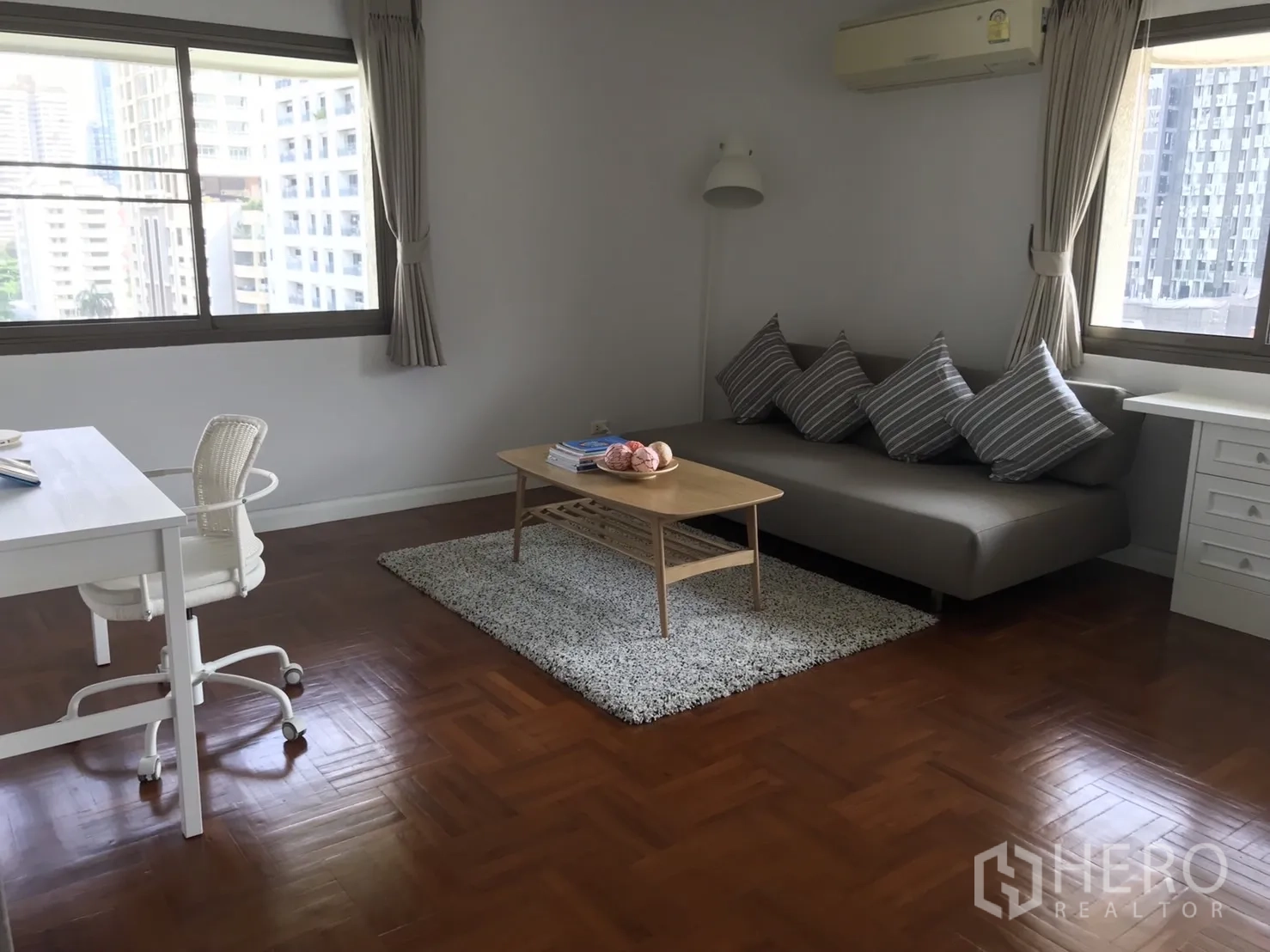 Condominium for rent in Bangkok - Corner study with gray sofa, coffee table and twin windows facing the skyline.
