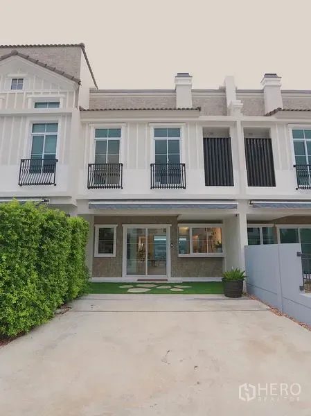 Townhouse for rent in Prawet, Bangkok - Two-storey townhouse exterior with driveway parking and trimmed front garden in Prawet, Bangkok.
