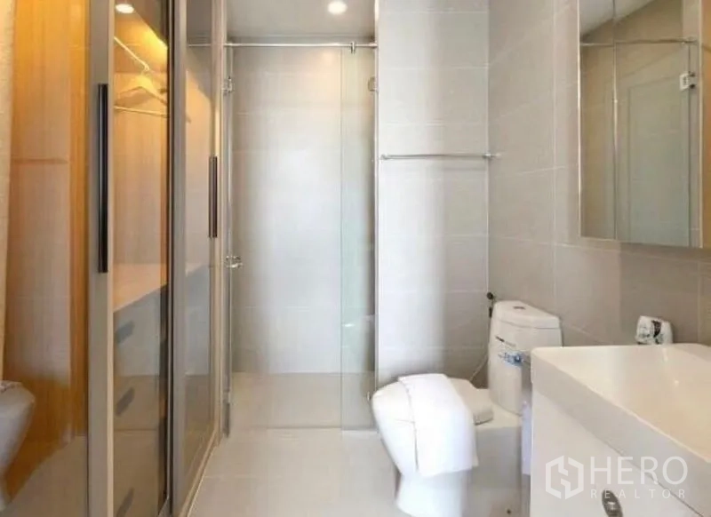 Condominium for rent in Pathum Wan, Bangkok - Clean bathroom with glass shower, vanity, and built-in wardrobe with sliding doors.