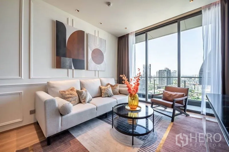 Condominium for rent in Khlong Toei, Bangkok - Contemporary living room with large windows and skyline view from the balcony.