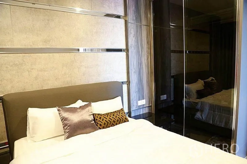 公寓 出租在Huai Khwang, Bangkok - 次卧带软包床头与镜面衣柜，深木色调。
