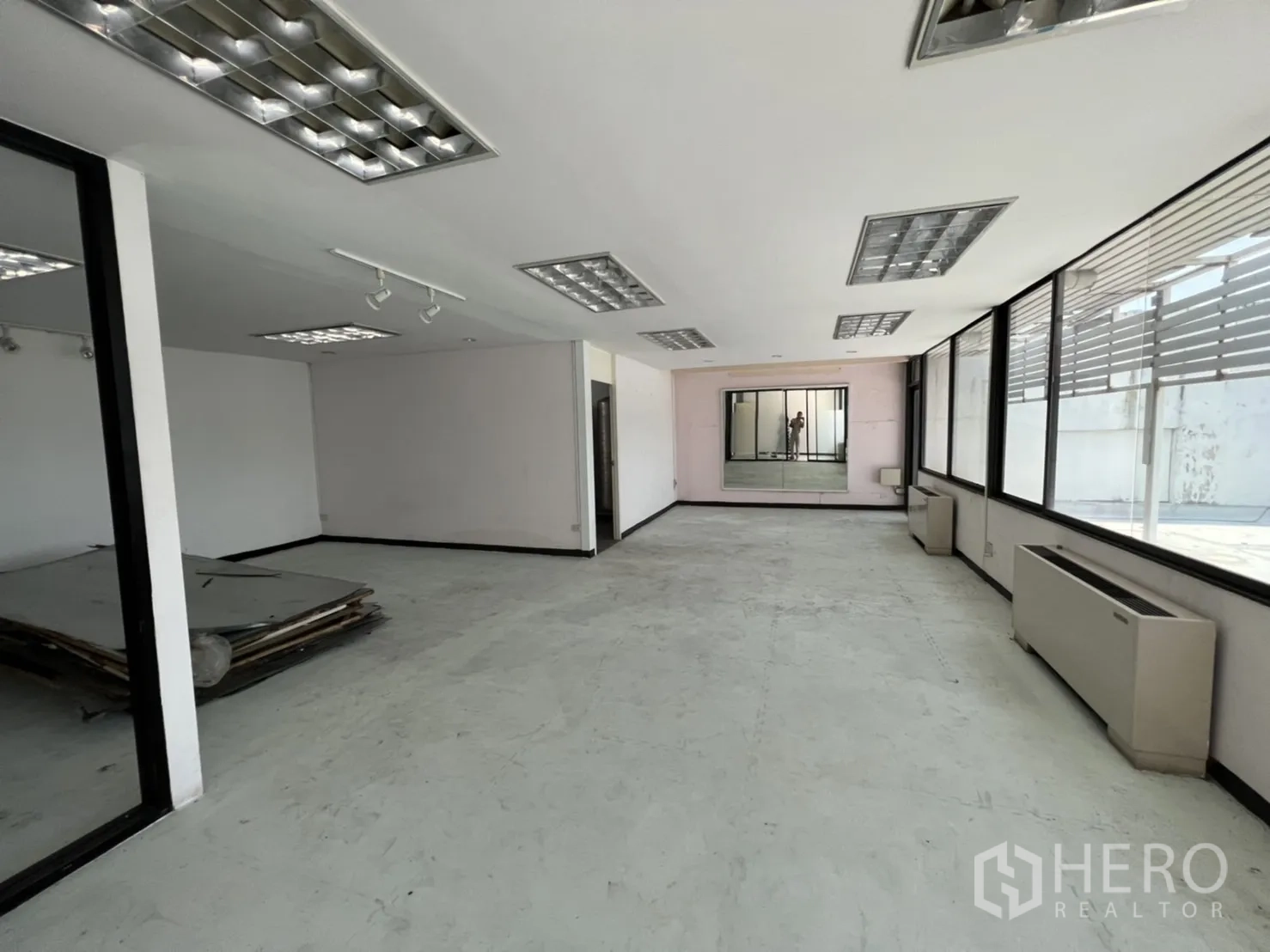 Shophouse for rent or sale in Watthana, Bangkok - Top-floor studio with large windows and exposed concrete flooring.