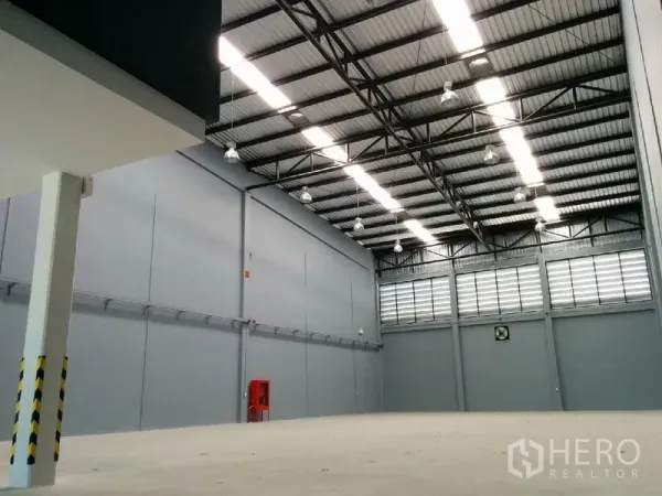 Factory for rent in Samut Prakan - Spacious warehouse interior featuring an 8-meter high steel truss roof and bright industrial lighting.