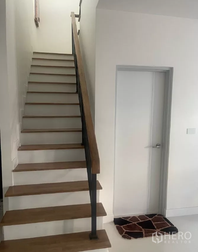Detached House for rent or sale in Saphan Sung, Bangkok - Staircase with wooden treads and a black handrail.