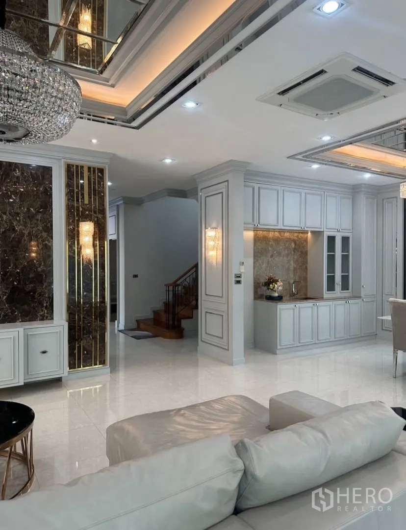 Detached House for rent or sale in Prawet, Bangkok - Grand two-storey facade with a stone tower, arched windows, covered multi-car carport, gate, and palm tree.