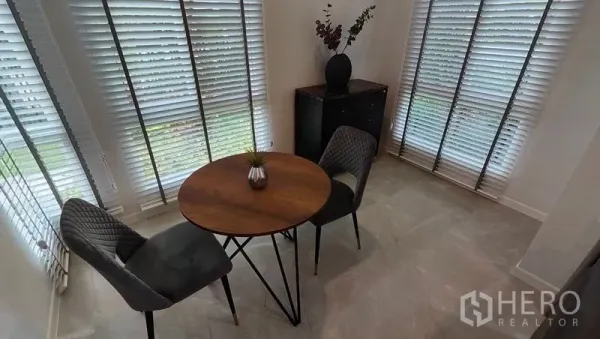 Detached House for rent in Prawet, Bangkok - Cozy breakfast nook with a round table and two chairs by corner windows with blinds.