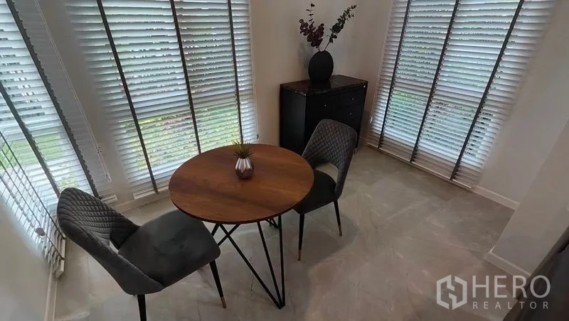Detached House for rent in Prawet, Bangkok - Cozy breakfast nook with a round table and two chairs by corner windows with blinds.