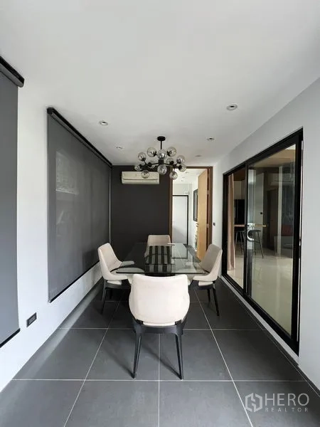 Townhouse for rent in Saphan Sung, Bangkok - Bright dining room with glass table, modern chandelier, and roller blinds.