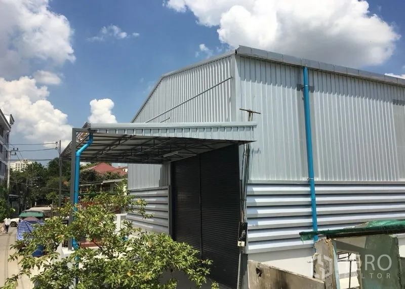 货栈 出租在Din Daeng, Bangkok - 金属板仓库侧视，卷闸门与雨棚清晰可见