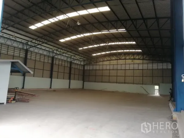 Warehouse for rent in Lat Krabang, Bangkok - Spacious warehouse interior in Lat Krabang with high steel truss roof, skylight panels, and smooth concrete floor.