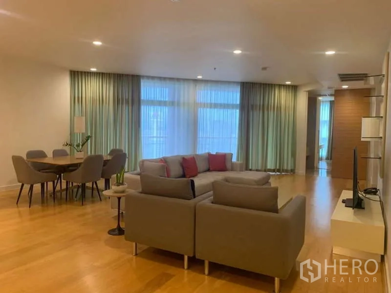 Condominium for rent in Bang Kho Laem, Bangkok - Open-plan living and dining area with wood floors and sectional sofa.