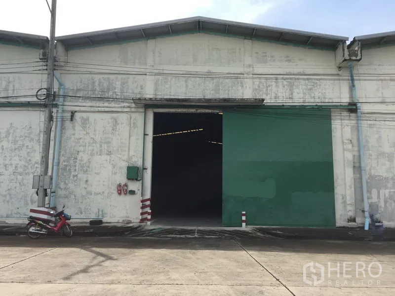 货栈 出租在Khlong Luang, Pathum Thani - 仓库外立面，绿色大滑门与装卸通道