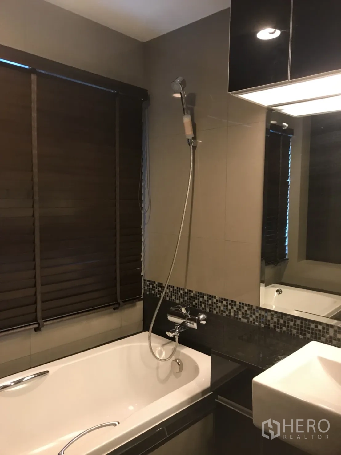 Condominium for rent in Khlong Toei, Bangkok - Contemporary bathroom featuring a soaking bathtub, handheld shower and mosaic tile accents.