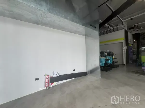 零售空间 出租 - 带金属包边的展示凹位与白色墙面，旁为开放销售区与工业风顶棚。