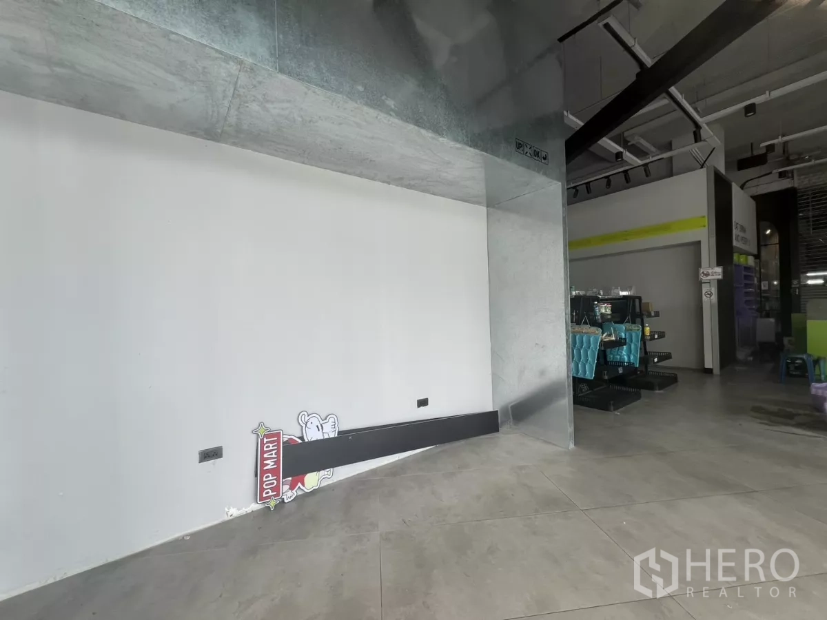 零售空间 出租 - 带金属包边的展示凹位与白色墙面，旁为开放销售区与工业风顶棚。