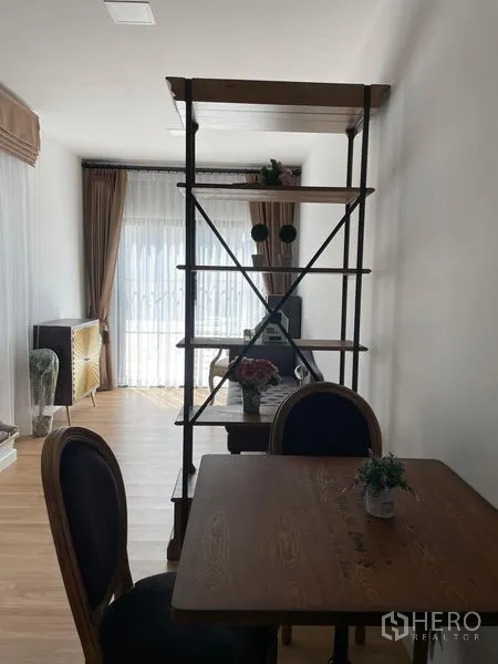 Townhouse for rent in Samut Prakan - Open living and dining area featuring industrial-style shelving, large window and light wood floors.