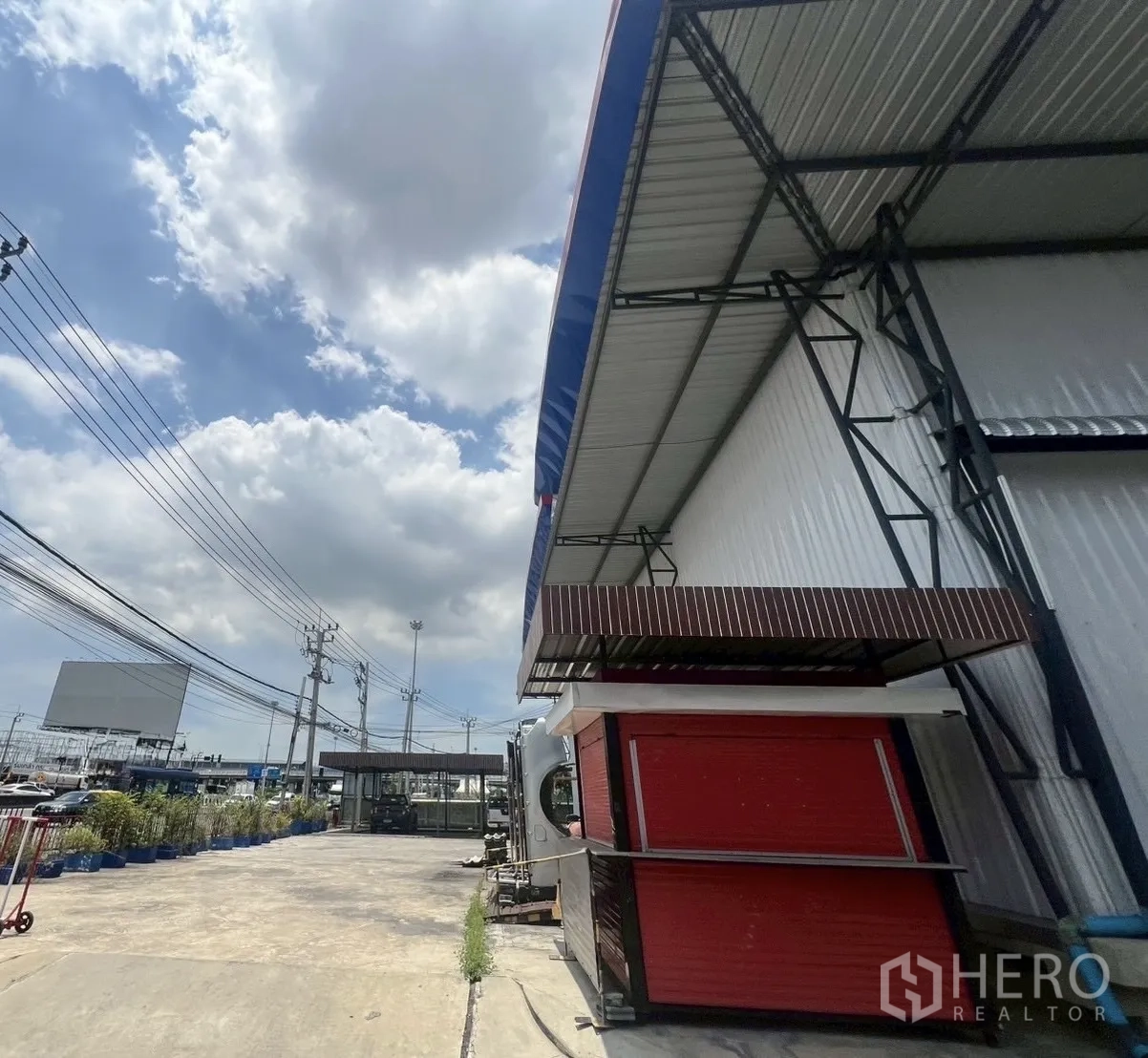 货栈 出租在Lat Krabang, Bangkok - 宽阔的混凝土车道与门岗，仓库旁可见路边电线设施。