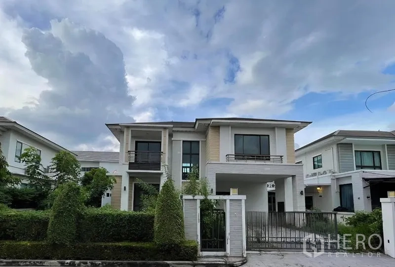 独立式住宅 出售在Lat Krabang, Bangkok - 邦普里现代两层独栋别墅正面，带金属大门与绿篱车道。