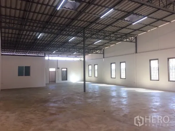 货栈 出租在Pathum Thani - 开放式仓储区，灯光明亮，带防护窗和光滑混凝土地面。
