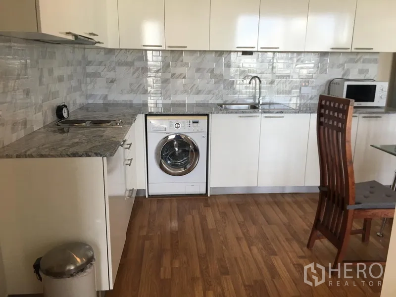 Condominium for rent in Watthana, Bangkok - Open-plan kitchen with built-in washing machine, long counter and ample storage.