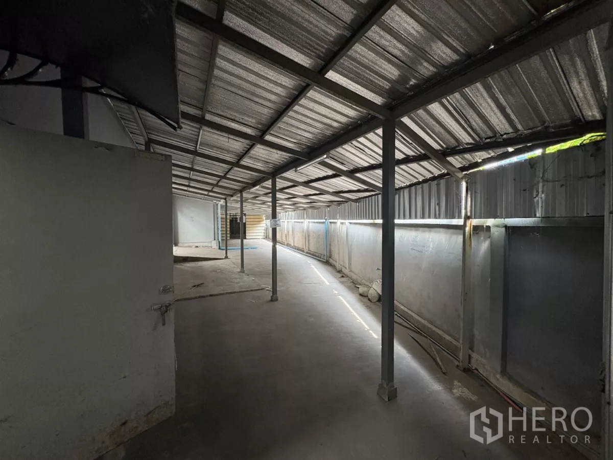 货栈 出租在Bang Phli, Samut Prakan - 仓库一侧的有顶步道，金属屋顶与立柱。