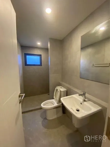联排别墅 出租在Prawet, Bangkok - 宽敞卫生间，含坐便器、洗手盆和带窗的淋浴区。
