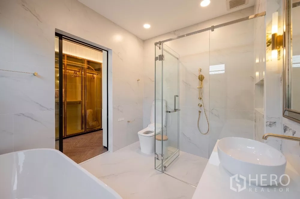 Detached House for rent or sale in Khlong Toei, Bangkok - Luxury bathroom with glass shower, freestanding tub, marble walls and gold fixtures.