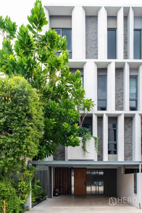 Townhouse for rent in Lat Phrao, Bangkok - Contemporary townhouse exterior with vertical fins and gated carport.