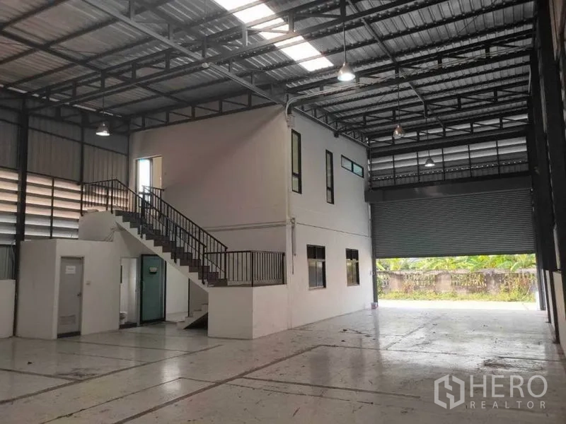 Warehouse for rent in Lam Luk Ka, Pathum Thani - Warehouse interior with two-storey office block and wide roller door.