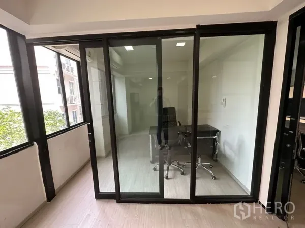 Office Space for rent in Khlong Toei, Bangkok - Private office with glass sliding doors, wood flooring, desk and chair, and leafy views.