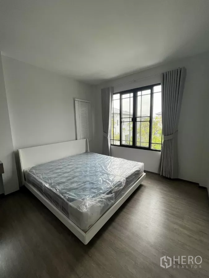 Detached House for rent or sale in Bang Phli, Samut Prakan - Master bedroom with a king-size bed frame, large window, and curtains.