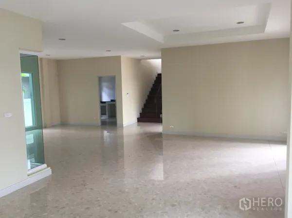 Detached House for sale in Saphan Sung, Bangkok - Spacious open-plan living room with glossy stone floors, recessed lighting, and a staircase.