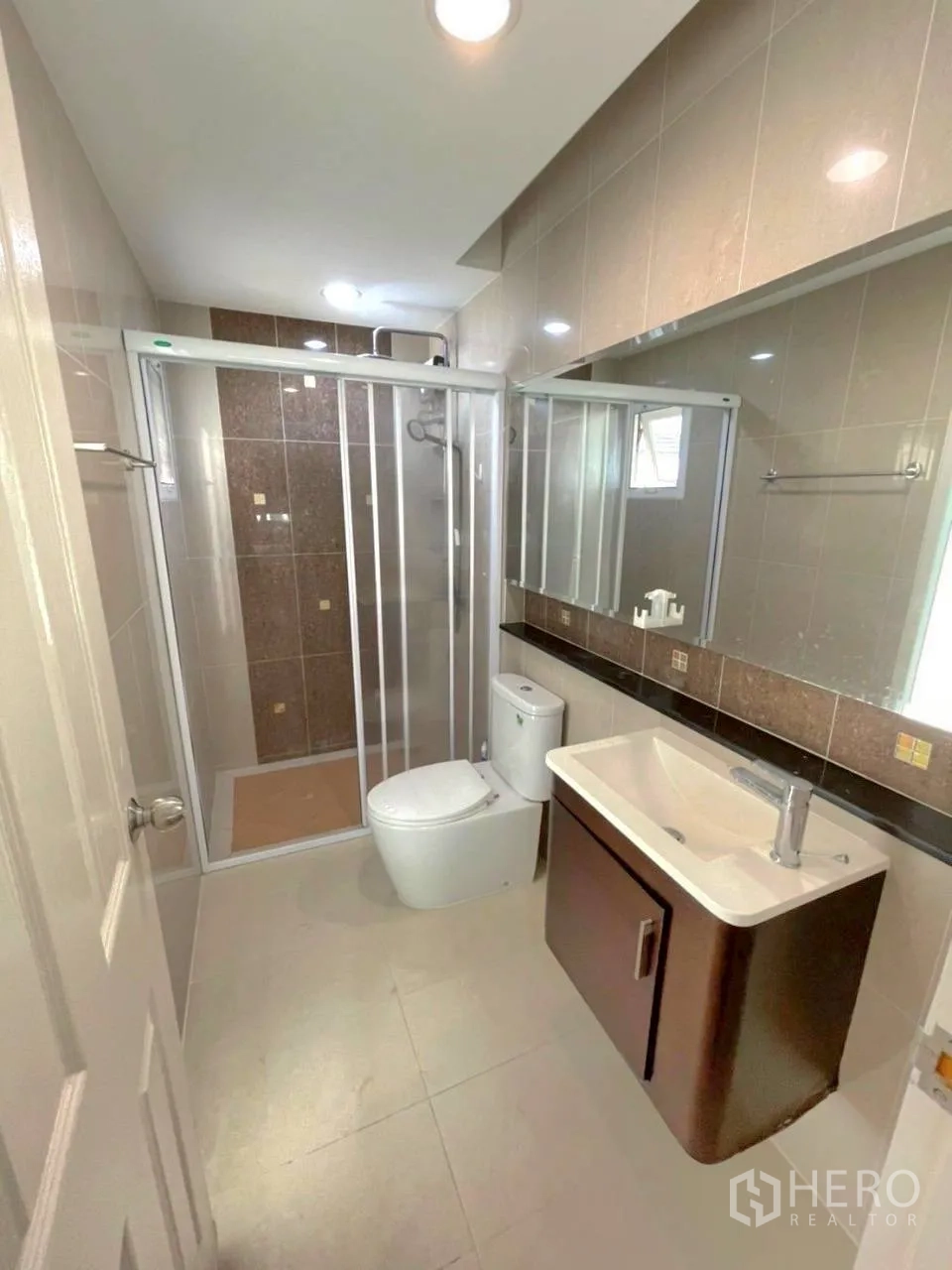 Townhouse for rent in Bang Kho Laem, Bangkok - Modern bathroom with glass shower enclosure, vanity, large mirror and toilet.