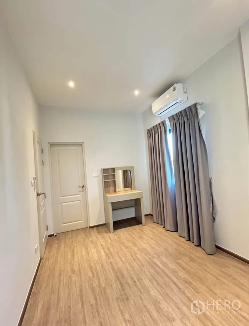 Semi-detached House for rent in Bang Phli, Samut Prakan - Bright bedroom with wood-look flooring, air conditioner, curtains and a built-in dressing table.