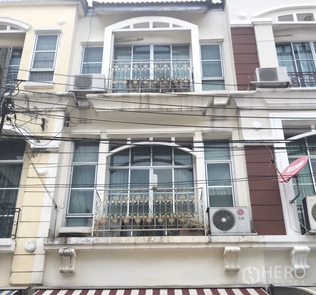 联排别墅 出租在Wang Thonglang, Bangkok - 三层联排别墅外立面，设阳台、锻铁栏杆与遮阳篷，外机可见。