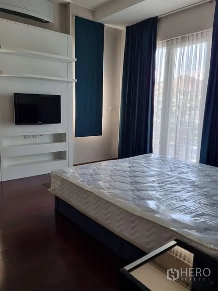 Detached House for sale in Chatuchak, Bangkok - Bright bedroom with large windows, blue curtains, wall-mounted TV and built-in shelving.