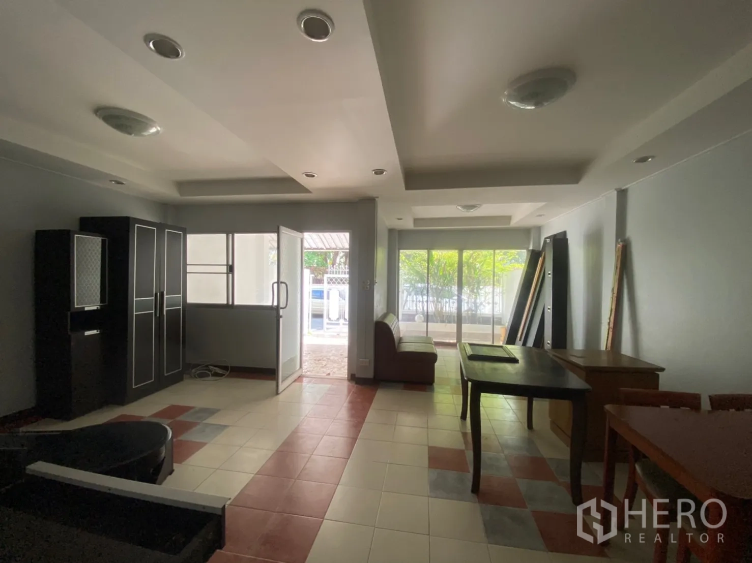 Townhouse for rent in Watthana, Bangkok - Open living and dining area with recessed ceiling, tiled floor and sliding doors to the terrace.