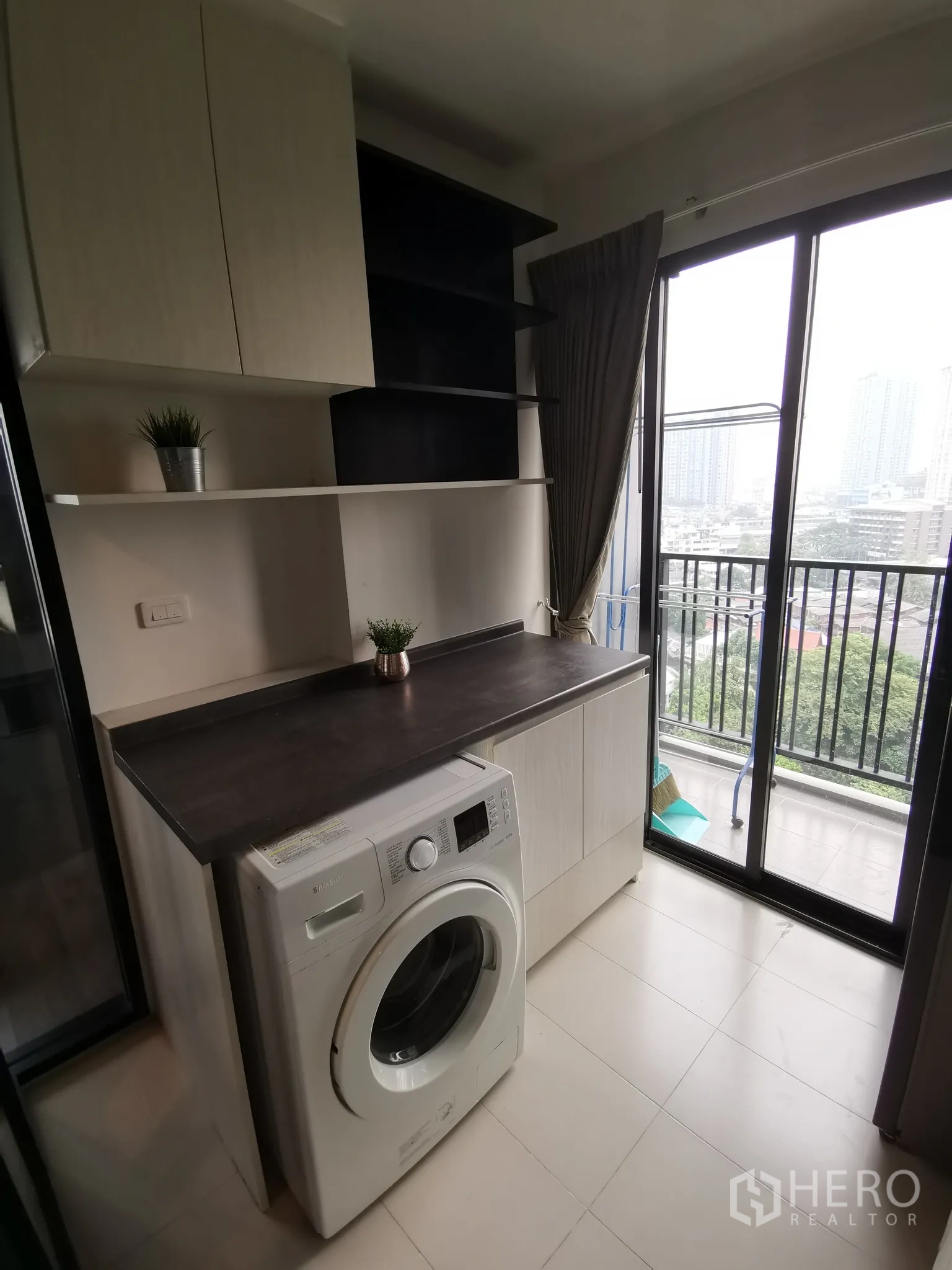 Condominium for rent or sale in Watthana, Bangkok - Laundry area with washing machine, storage cabinets and access to the balcony.