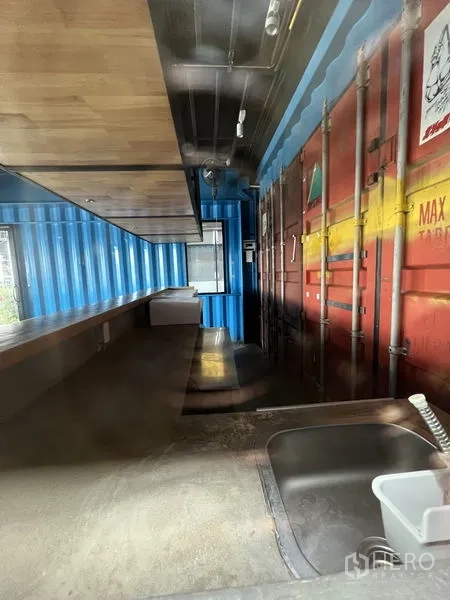 零售空间 出租 - 后场备餐区，带水槽、长操作台与集装箱墙板。