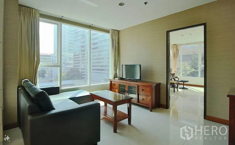 公寓 出售在Watthana, Bangkok - 客厅配电视柜与沙发，落地窗俯瞰阿索克商圈高楼。